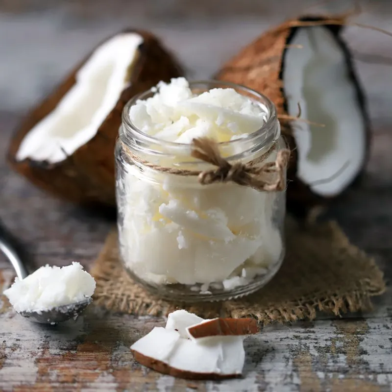 Kokosfett im Glas neben einer geöffneten Kokosnuss